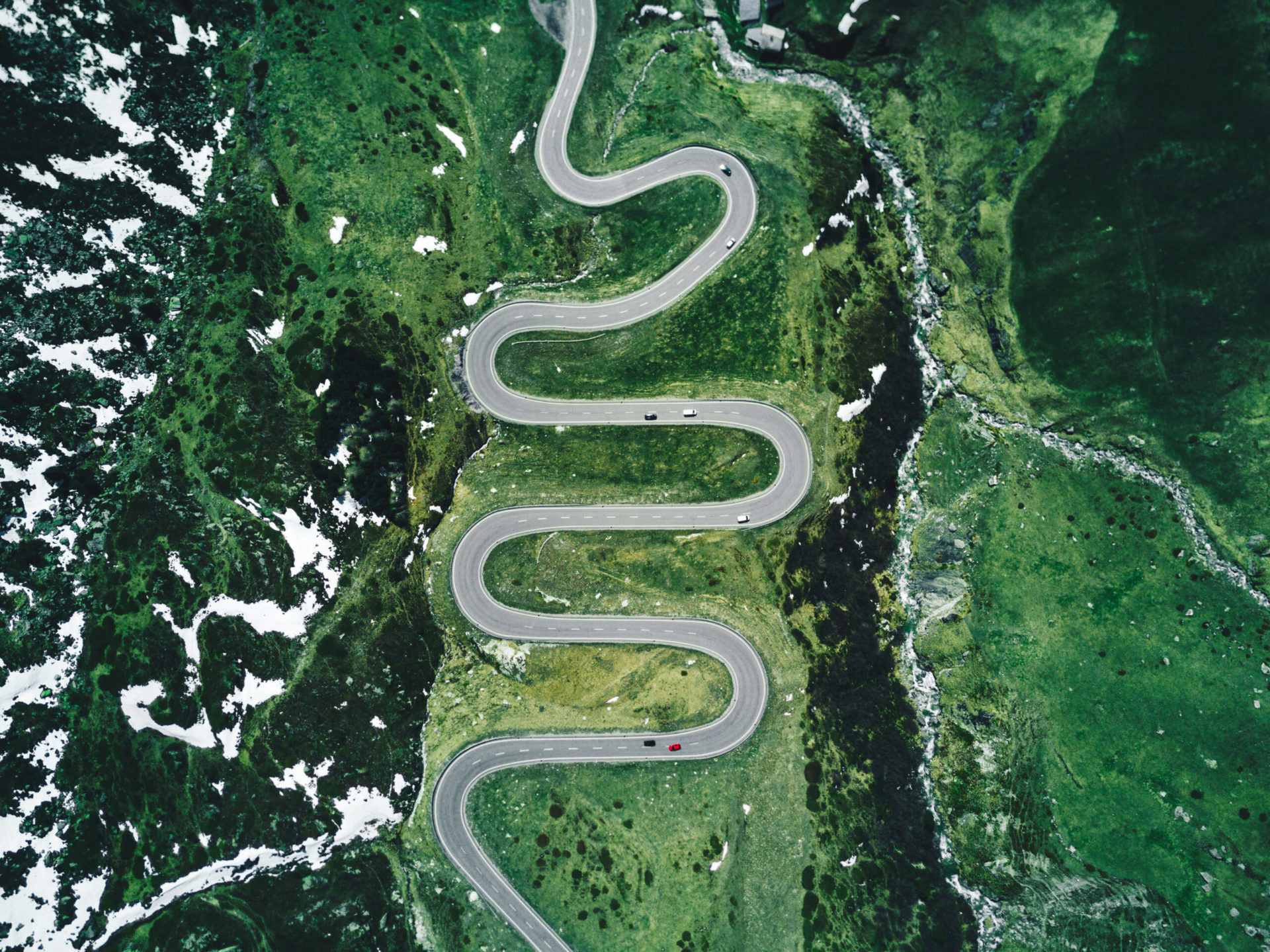 Sky view in switzerland showing a zig-zag road on a mountain with cars driving to represent the carrer lab service